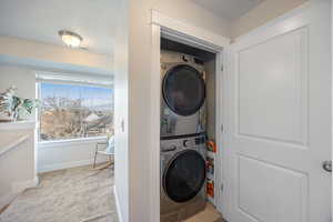 Washroom with light colored carpet and stacked washer / drying machine