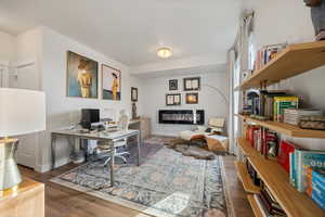 Office area featuring wood finished floors and a glass covered fireplace