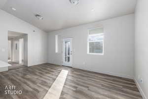 Empty room featuring vaulted ceiling and wood finished floors