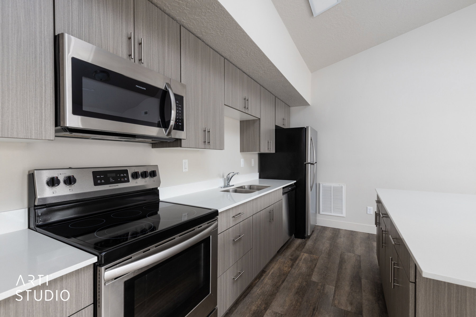 Kitchen with appliances with stainless steel finishes, dark wood-type flooring, modern cabinets, dark brown cabinetry, and light stone countertops