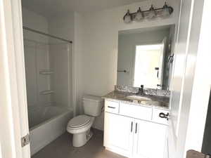 Bathroom featuring vanity, tub / shower combination, and dark tile patterned floors