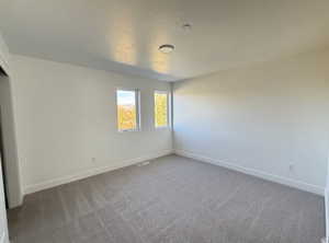 Spare room featuring light carpet and baseboards