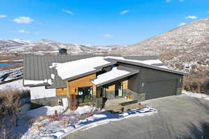 View of front facade with stone siding, a mountain view, driveway, a garage, and a porch