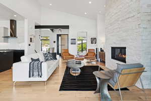 Living area featuring a fireplace, light wood finished floors, recessed lighting, and high vaulted ceiling