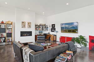 Living room with concrete flooring, a glass covered fireplace, and recessed lighting
