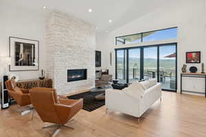 Living room featuring high vaulted ceiling, light wood finished floors, a fireplace, and recessed lighting