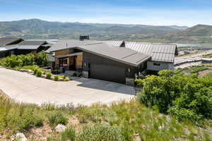 Modern home with a mountain view, stone siding, driveway, a standing seam roof, and a garage