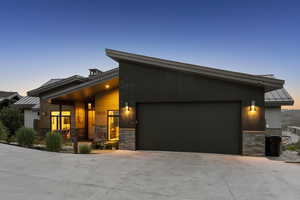 Contemporary home with stone siding, a standing seam roof, driveway, and an attached garage