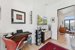 Office space with light wood-style flooring, lofted ceiling, and recessed lighting