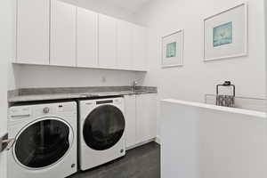 Laundry area with washer and dryer, cabinet space, and dark tile patterned flooring