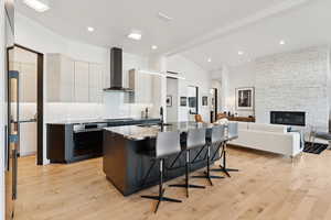 Kitchen with open floor plan, dark stone counters, a center island with sink, a kitchen breakfast bar, and oven