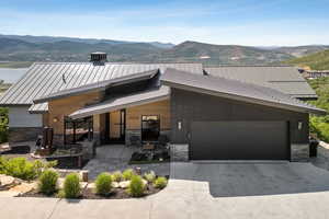 Contemporary home featuring stone siding, a mountain view, a standing seam roof, driveway, and a metal roof