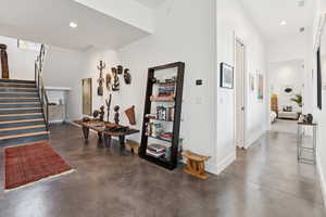 Corridor with stairs, concrete floors, and recessed lighting