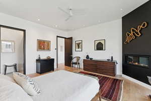 Bedroom with ceiling fan, light wood finished floors, recessed lighting, and a fireplace