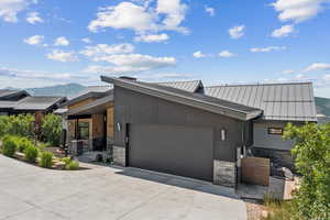 View of front facade featuring stone siding, concrete driveway, a mountain view, and an attached garage