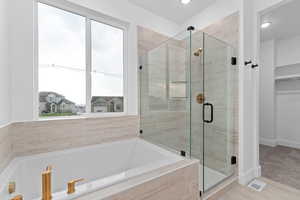 Full bath with a stall shower, a bath, and a walk in closet