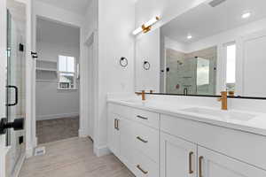 Bathroom with double vanity, a shower stall, and a spacious closet