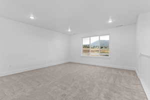 Empty room featuring light carpet, a mountain view, and recessed lighting