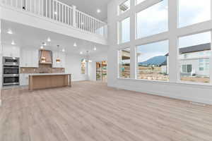 Unfurnished living room with light wood-style floors, a mountain view, a high ceiling, and recessed lighting