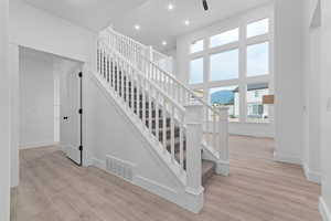 Stairway with wood finished floors, recessed lighting, and a towering ceiling