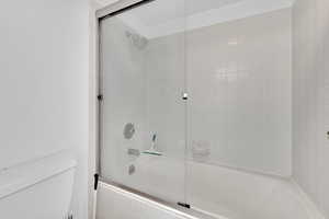 Primary bath  featuring enclosed tub / shower combo and toilet