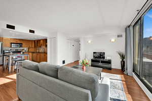 Open living room  and dine-in kitchen featuring LVP floors, abundant natural light, and balcony access