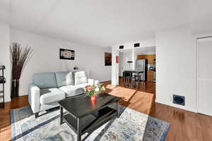 Open living room  and dine-in kitchen featuring LVP floors, abundant natural light, and balcony access