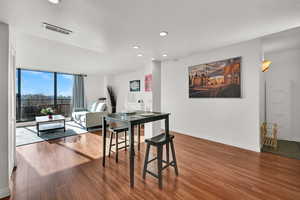 Open living room  and dine-in kitchen featuring LVP floors, abundant natural light, and balcony access