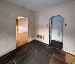 Empty room featuring arched walkways and a textured ceiling