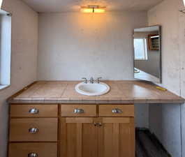 Bathroom featuring a textured wall and vanity