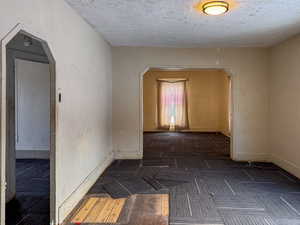 Unfurnished room featuring arched walkways and a textured ceiling
