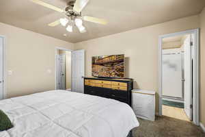 Bedroom with dark carpet, ceiling fan, and ensuite bathroom