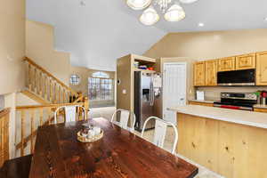 Dining space featuring a chandelier, stairs, and high vaulted ceiling