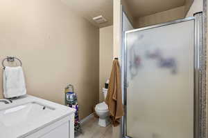 Full bathroom with vanity, a shower stall, light wood-style floors, and a textured ceiling