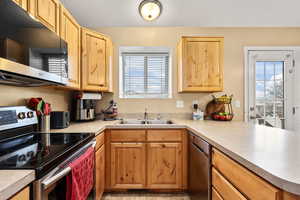 Kitchen with appliances with stainless steel finishes, light countertops, and light brown cabinetry