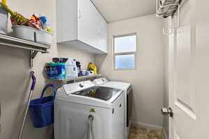 Laundry room featuring cabinet space, washer and dryer, and a textured ceiling