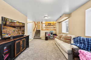 Living area featuring stairway, a textured ceiling, and light carpet