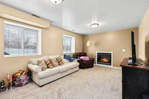Living room featuring a glass covered fireplace, carpet floors, and a textured ceiling