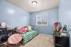 Bedroom with a textured ceiling and light colored carpet