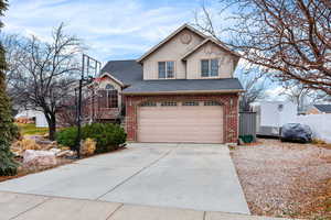 Traditional-style home featuring brick siding, a shingled roof, and driveway