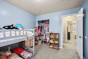 Bedroom featuring light carpet, a closet, and a textured ceiling