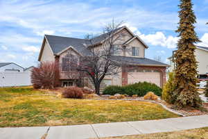 Traditional-style home with brick siding, a shingled roof, and an attached garage