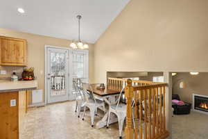 Dining room featuring a chandelier, high vaulted ceiling, and a glass covered fireplace