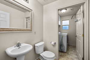 Bathroom with a textured ceiling, separate washer and dryer, and stone finish floors