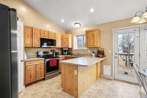 Kitchen featuring stainless steel appliances, light countertops, a peninsula, recessed lighting, and vaulted ceiling