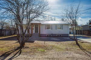 View of front facade featuring a metal roof, a carport, driveway, and entry steps