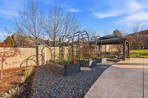 View of patio with a gazebo and a vegetable garden