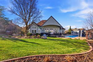 Back of property with a patio area, french doors, stone siding, an outdoor pool, and a yard