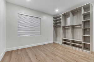 Walk in closet with light wood-style floors