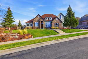 View of front facade featuring stone siding, a front lawn, and stucco siding